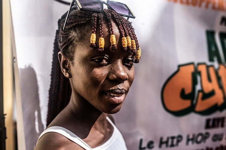 A young woman with braids looks into the camera.