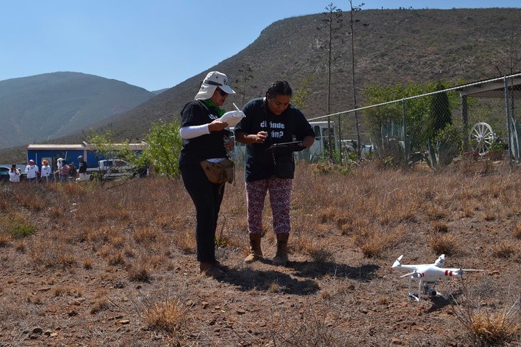 Two people stand outside in a desert launching a drone.